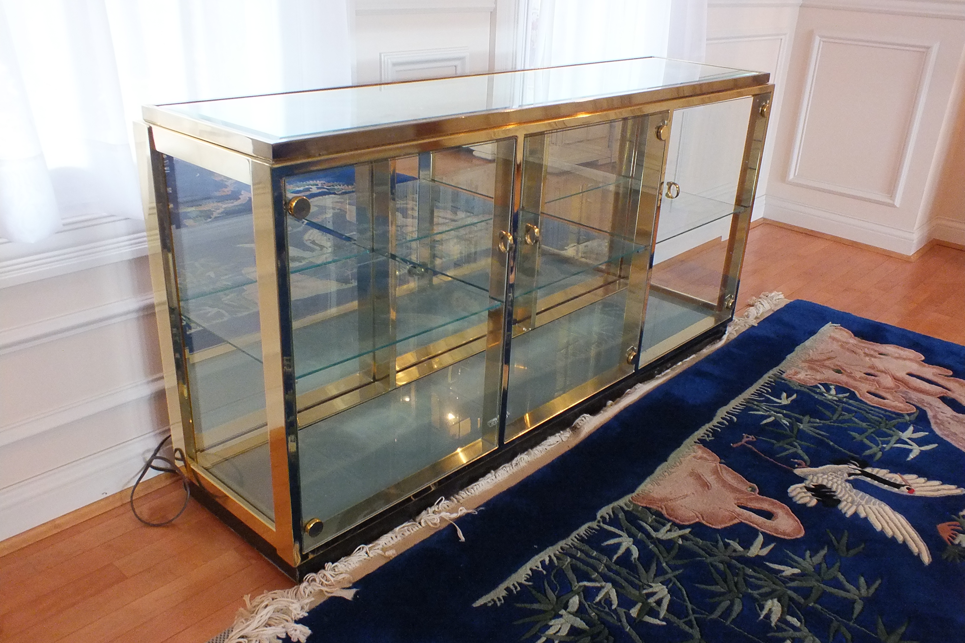 A brass and glass display case with beveled mirror top