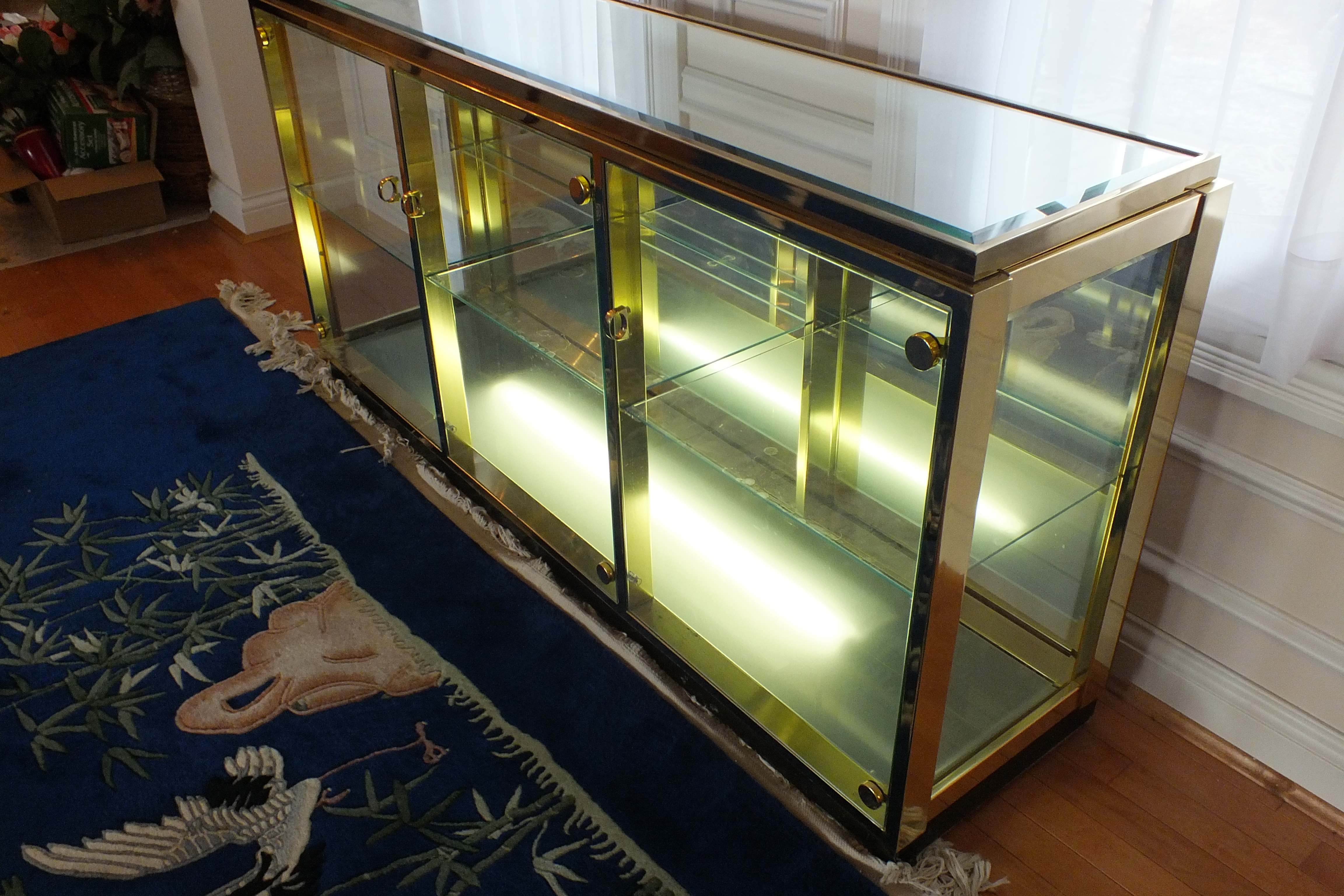 A brass and glass display case with beveled mirror top