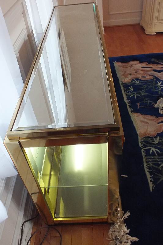 A brass and glass display case with beveled mirror top