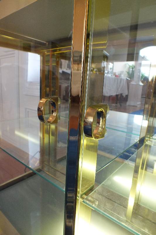 A brass and glass display case with beveled mirror top