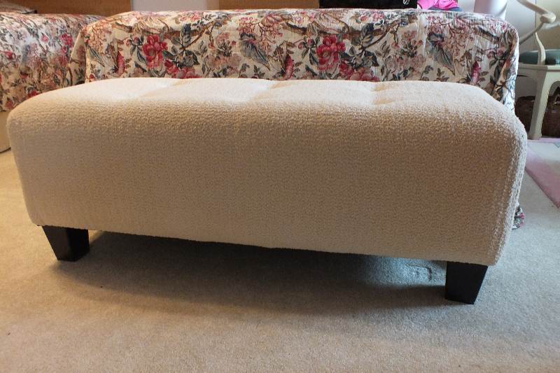 A Contemporary ottoman with button tufted seat upholstered in a soft white cotton chenille fabric