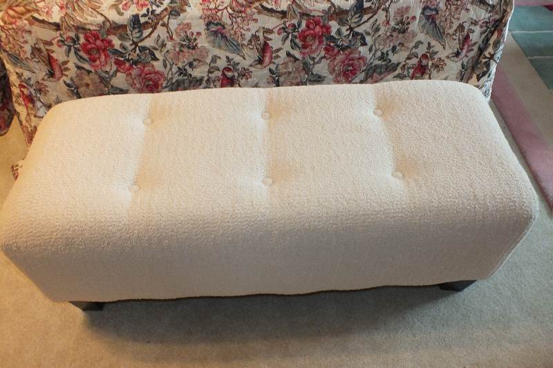 A Contemporary ottoman with button tufted seat upholstered in a soft white cotton chenille fabric