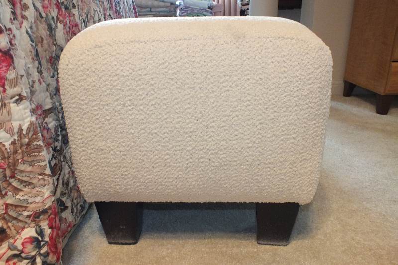 A Contemporary ottoman with button tufted seat upholstered in a soft white cotton chenille fabric