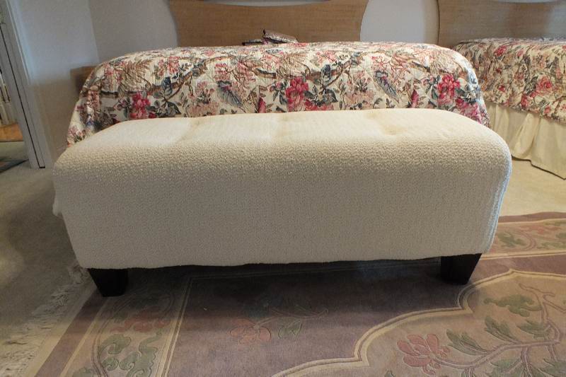 A Contemporary ottoman with button tufted seat upholstered in a soft white cotton chenille fabric