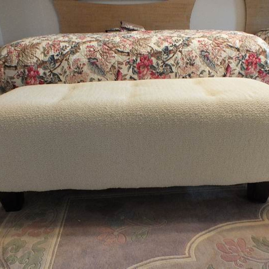 A Contemporary ottoman with button tufted seat upholstered in a soft white cotton chenille fabric