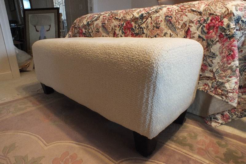 A Contemporary ottoman with button tufted seat upholstered in a soft white cotton chenille fabric