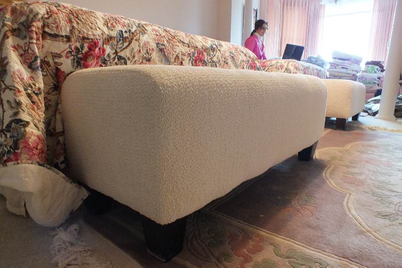 A Contemporary ottoman with button tufted seat upholstered in a soft white cotton chenille fabric