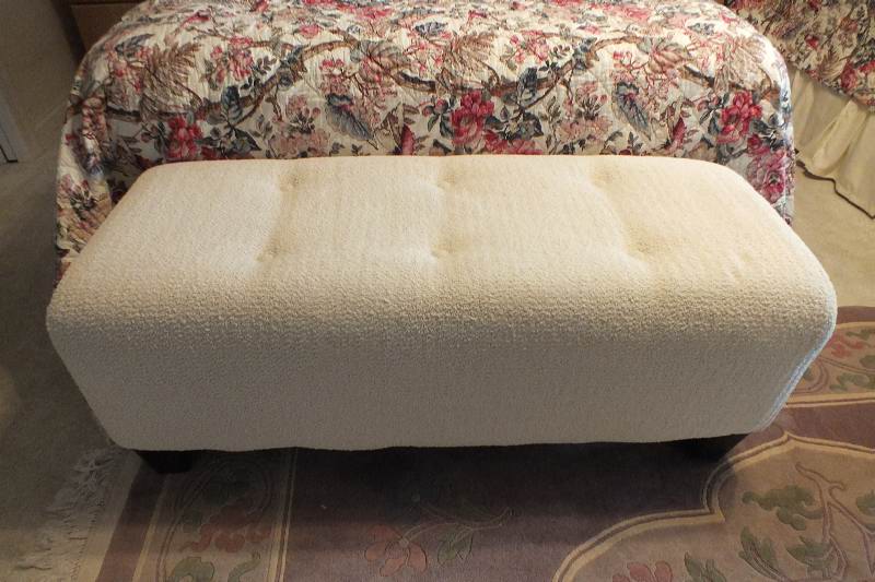 A Contemporary ottoman with button tufted seat upholstered in a soft white cotton chenille fabric