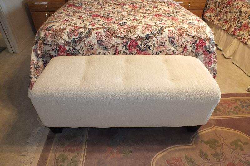 A Contemporary ottoman with button tufted seat upholstered in a soft white cotton chenille fabric