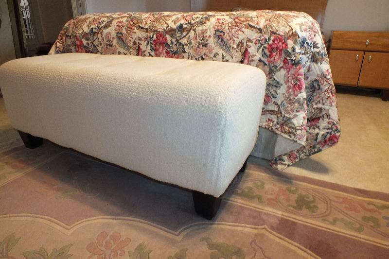 A Contemporary ottoman with button tufted seat upholstered in a soft white cotton chenille fabric