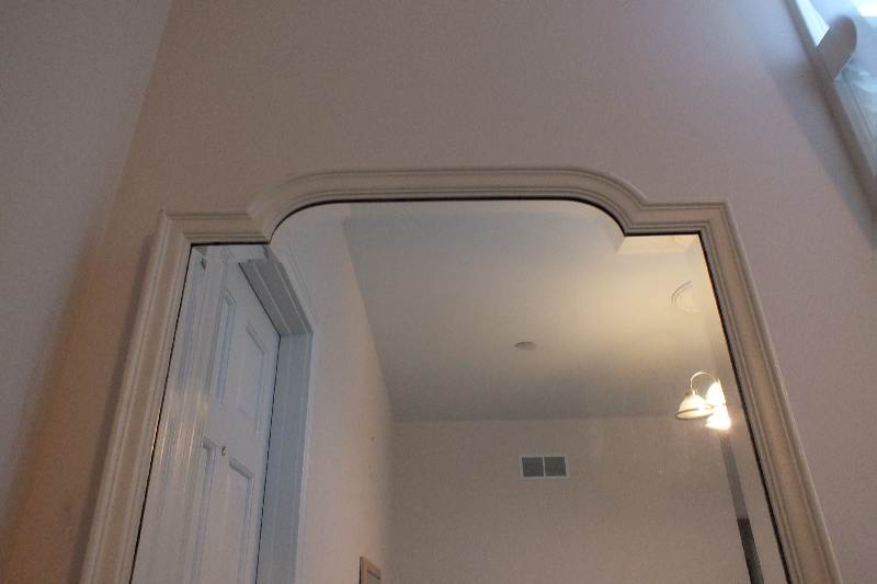 A painted wood framed beveled edge mirror repurposed as a wall unit