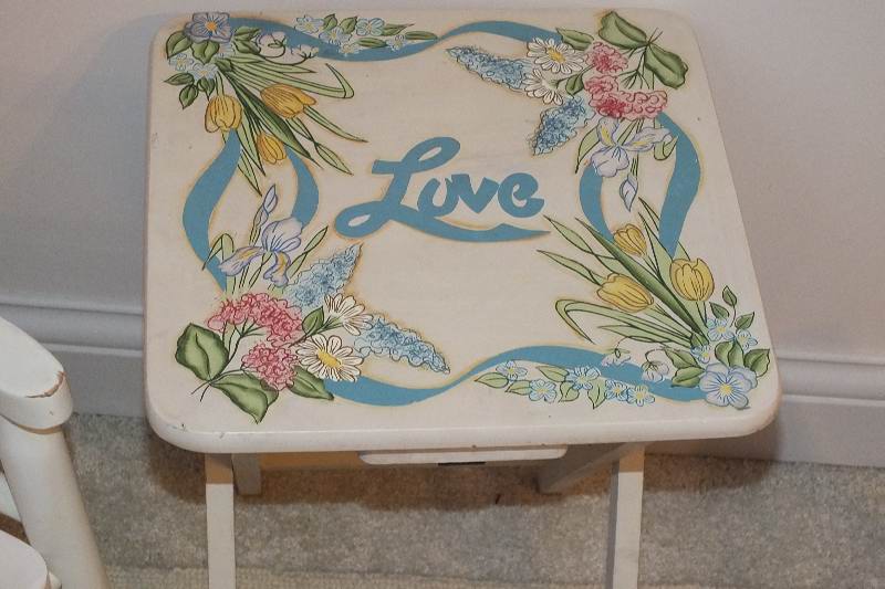 A cute set of furniture which consists of a white wood rocker from Kidcraft, a folding table with a painted "love" design, a vintage wood footstool-nice for reaching the sink, a folding chair stool with hand painted floral appliqués and a small hook rug h