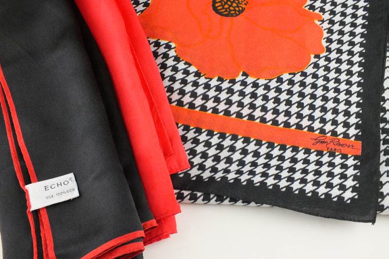 A trio of silk scarves which includes a black, white and red patterned scarf designed by Jim Renoir, Paris; a black scarf with red border from Echo and a vibrant Chinese red scarf