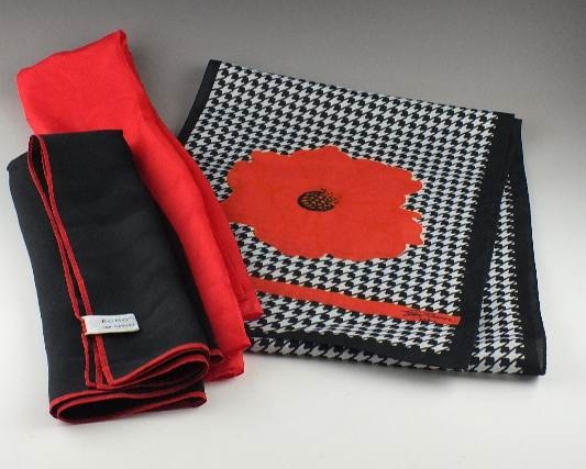 A trio of silk scarves which includes a black, white and red patterned scarf designed by Jim Renoir, Paris; a black scarf with red border from Echo and a vibrant Chinese red scarf