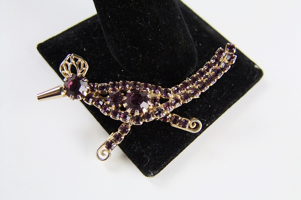 Hobe' roadrunner pin bejeweled with amethyst hued prong set crystal rhinestones