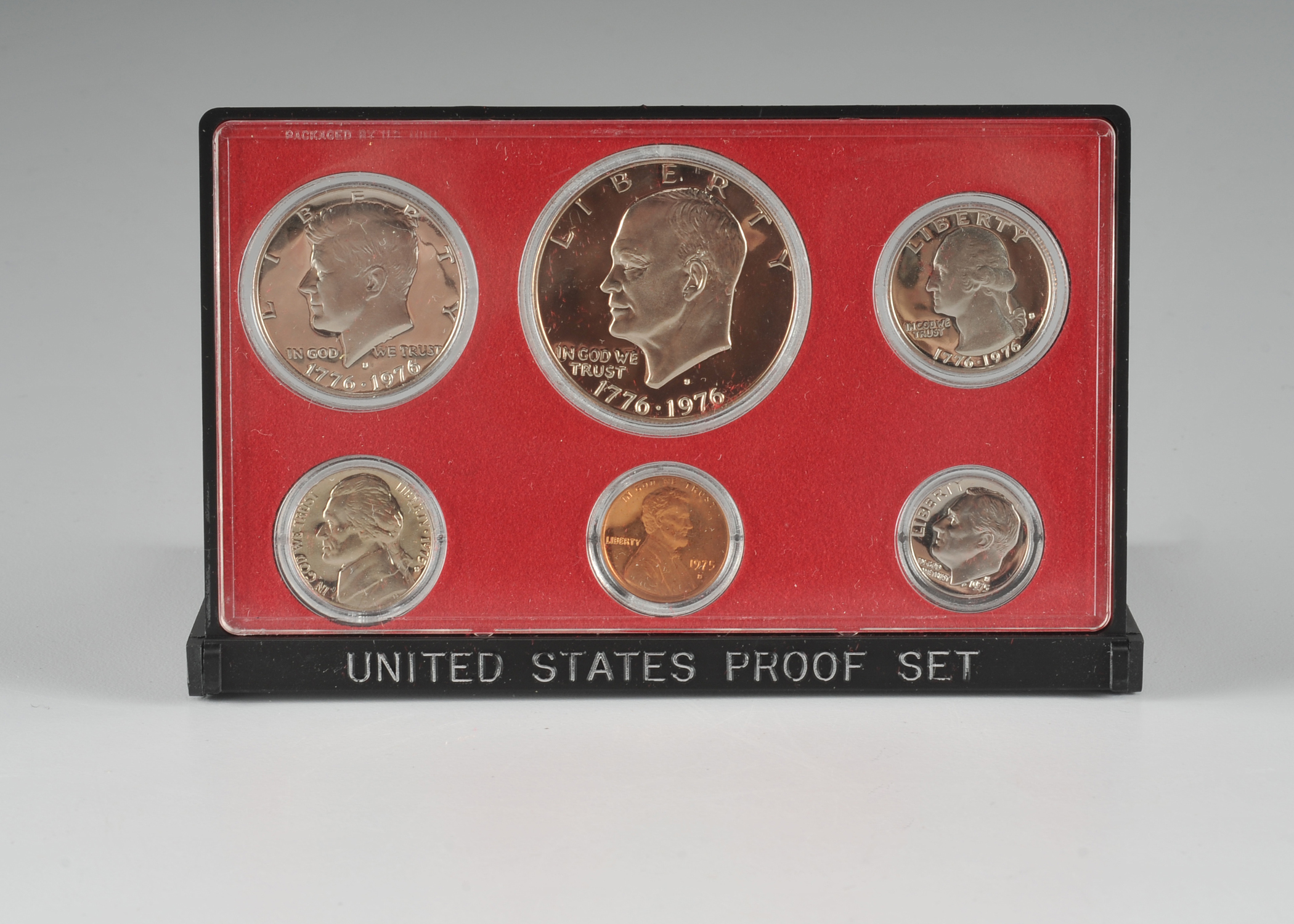 1975 U.S. Proof set including Eisenhower dollar, JFK half dollar, Washington quarter, Roosevelt dime, Jefferson nickel, and Lincoln penny