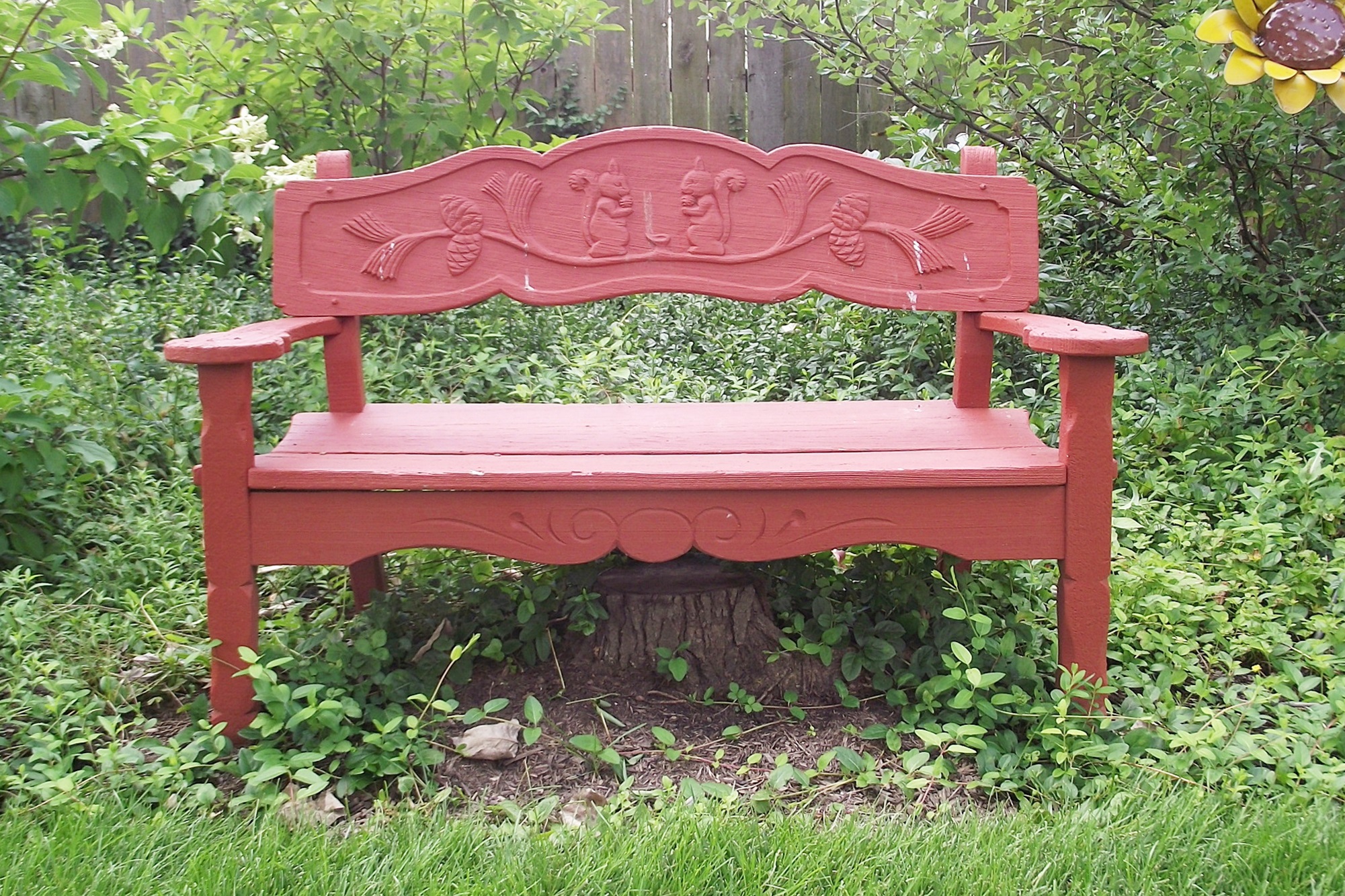 Vintage wooden garden bench with carved squirrel motif.