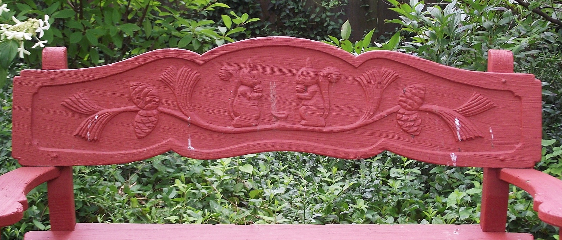 Vintage wooden garden bench with carved squirrel motif.