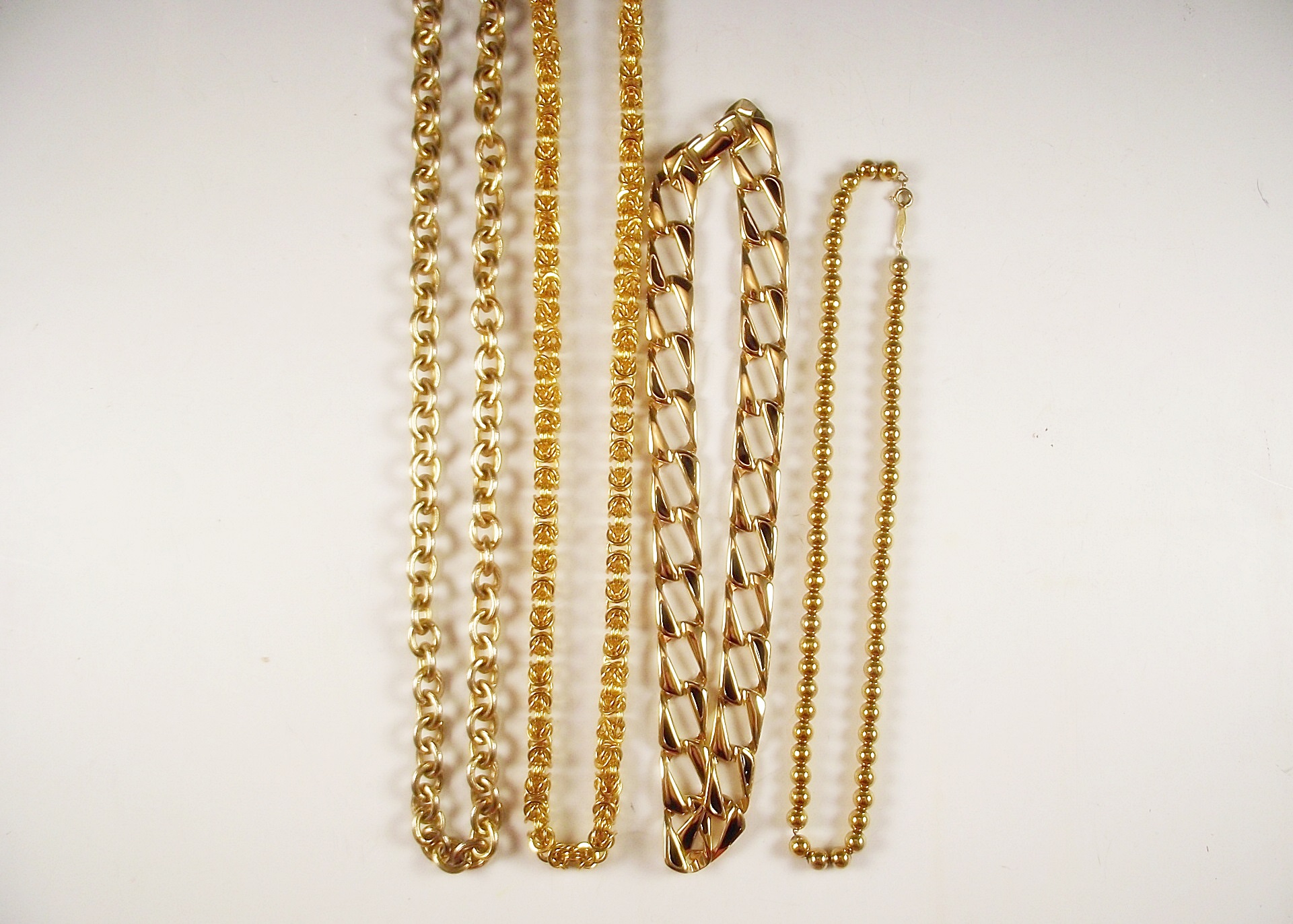 Four gold tone necklaces.