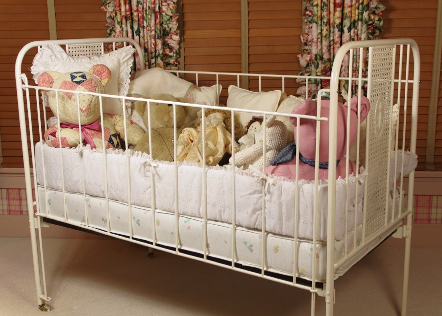 Cast Iron Crib, circa 1940-50, filled with Dolls, Bunnies, and Lace Pillows