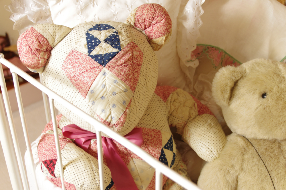 Cast Iron Crib, circa 1940-50, filled with Dolls, Bunnies, and Lace Pillows