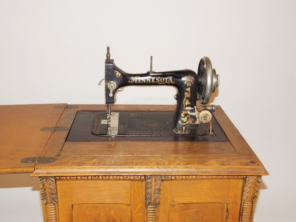 An Antique Minnesota Model B Treadle Sewing Machine in a Tiger oak Cabinet