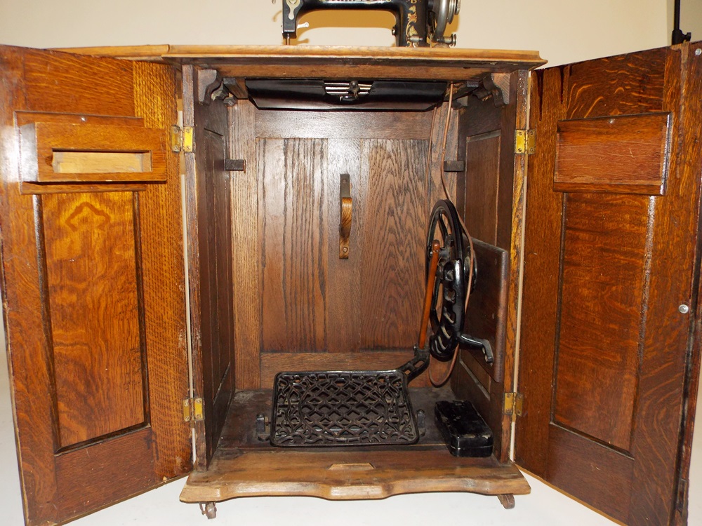 An Antique Minnesota Model B Treadle Sewing Machine in a Tiger oak Cabinet