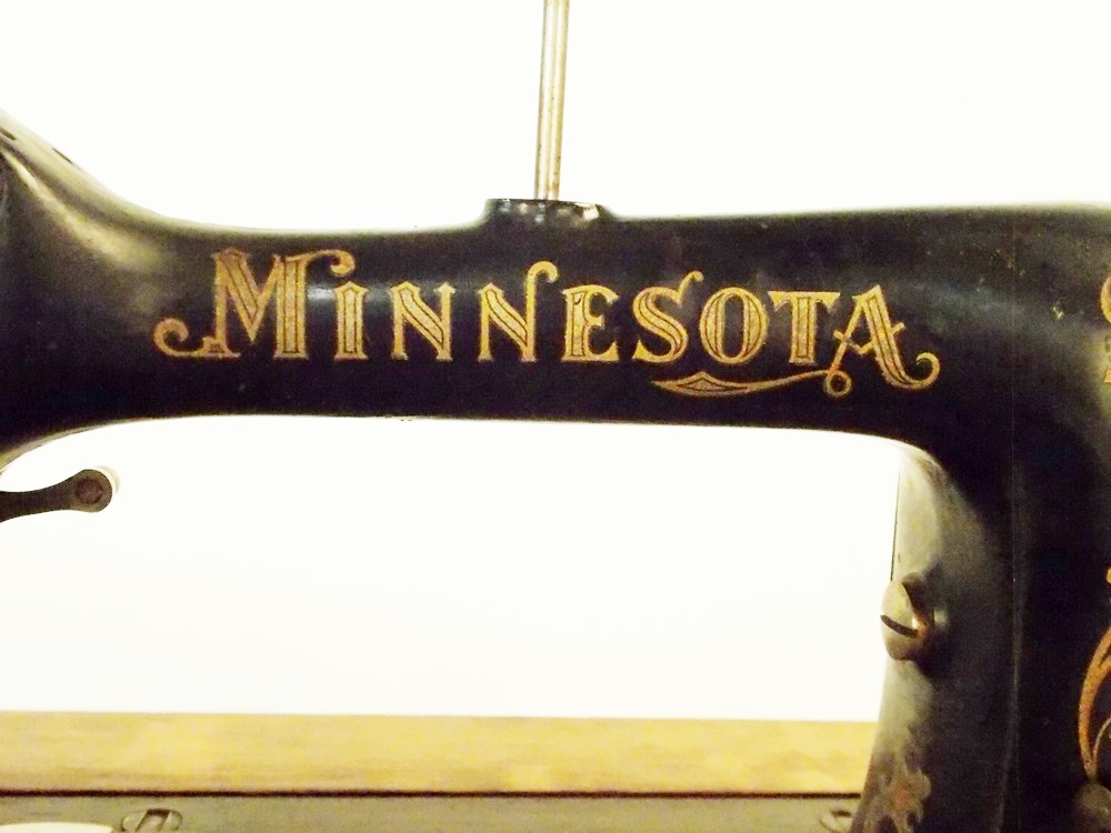 An Antique Minnesota Model B Treadle Sewing Machine in a Tiger oak Cabinet