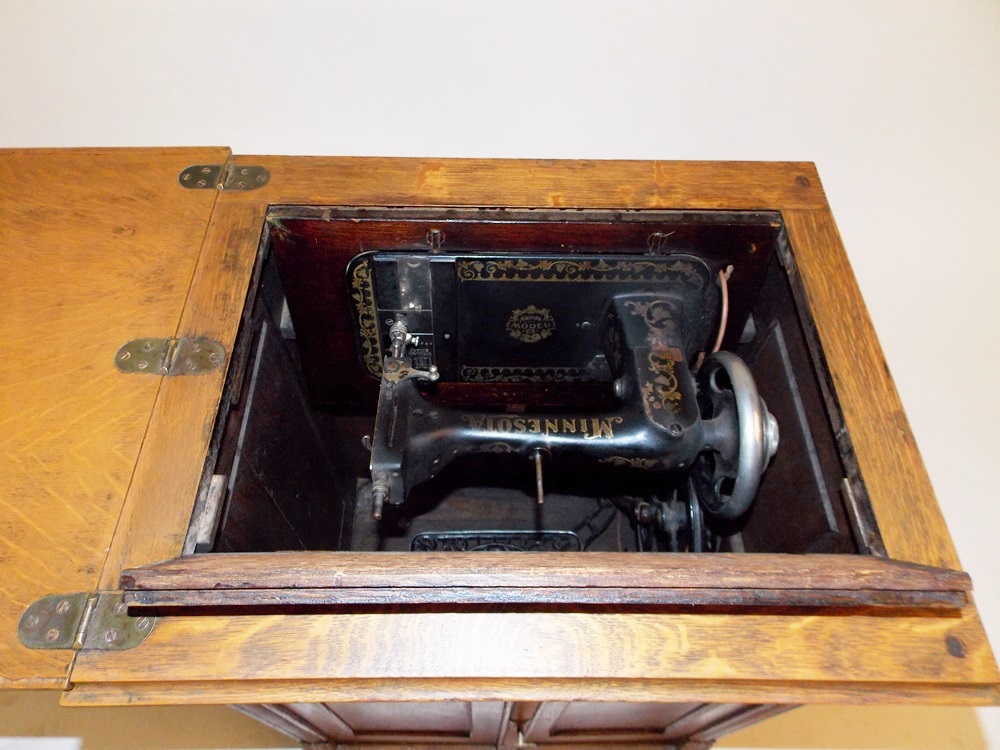 An Antique Minnesota Model B Treadle Sewing Machine in a Tiger oak Cabinet