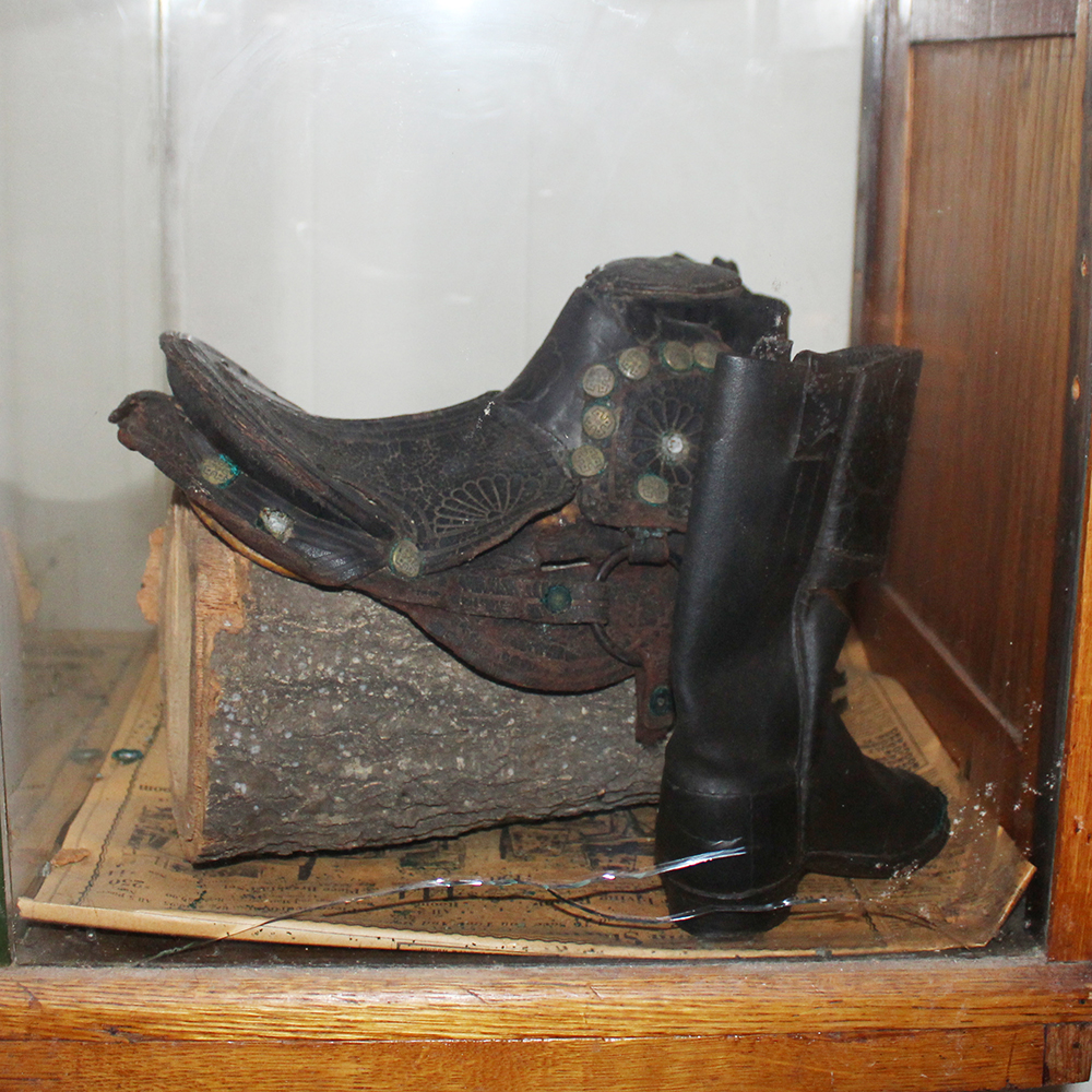 Antique Display Case Containing Children's Boots and Saddle