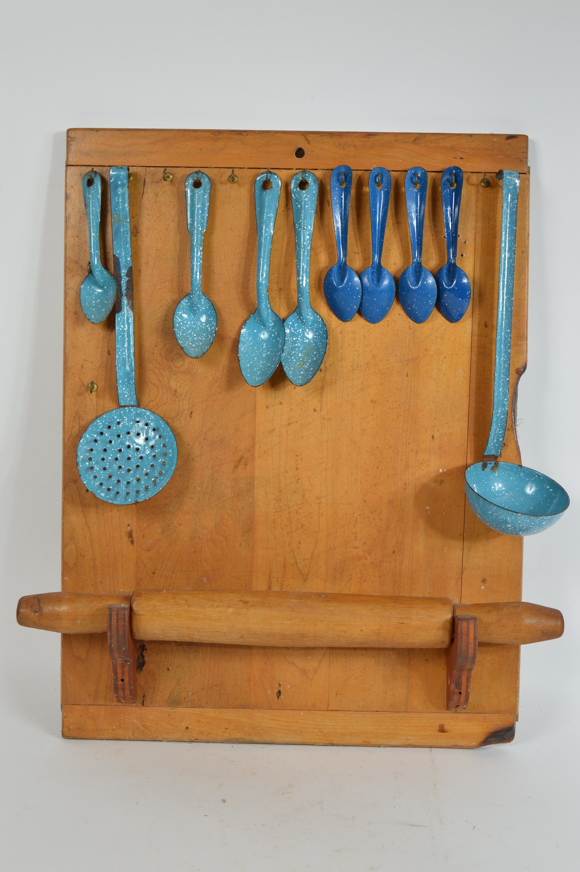 Collection of Speckled Enamel Ware Utensils Mounted on a Cutting Board