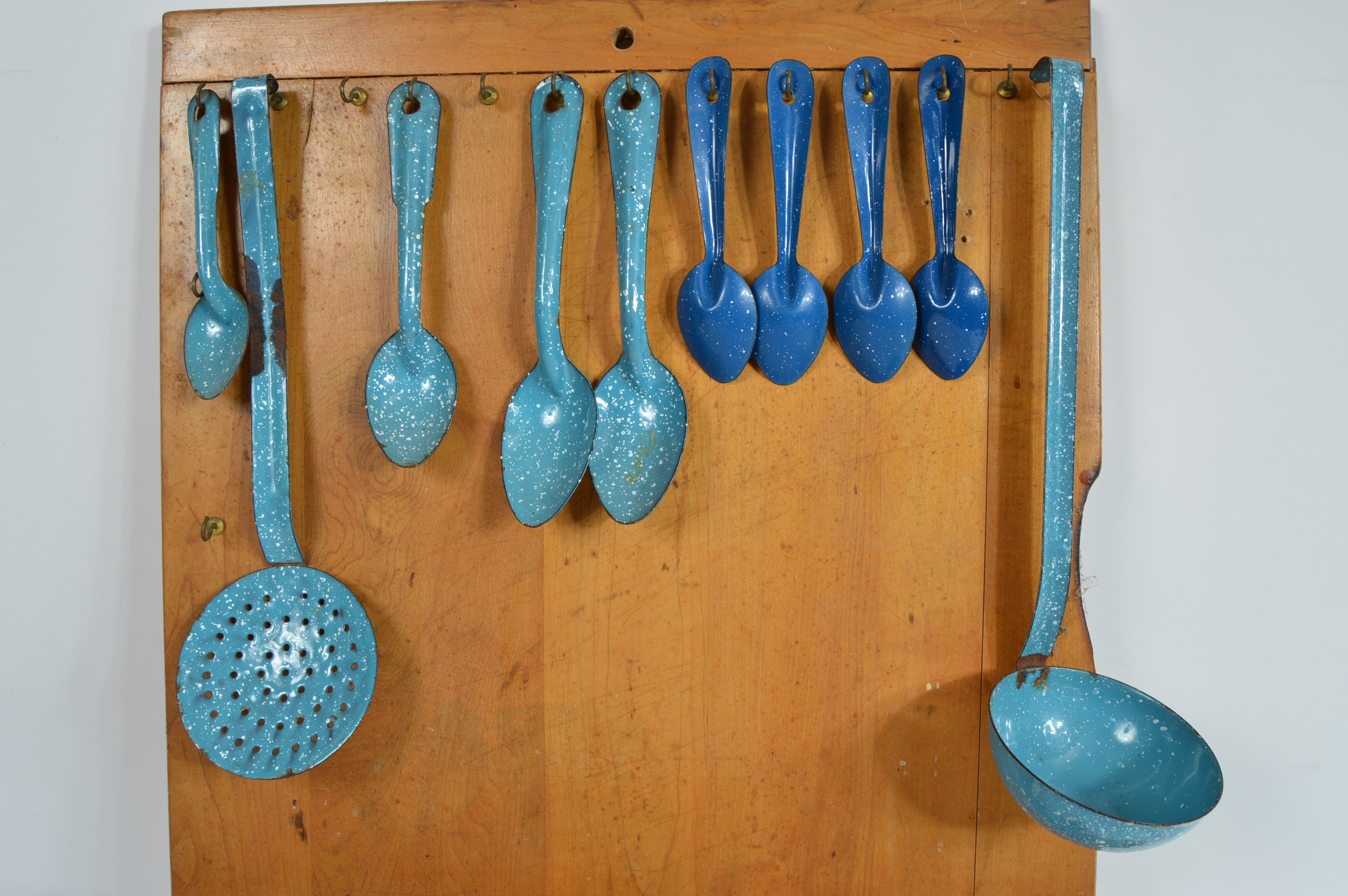 Collection of Speckled Enamel Ware Utensils Mounted on a Cutting Board