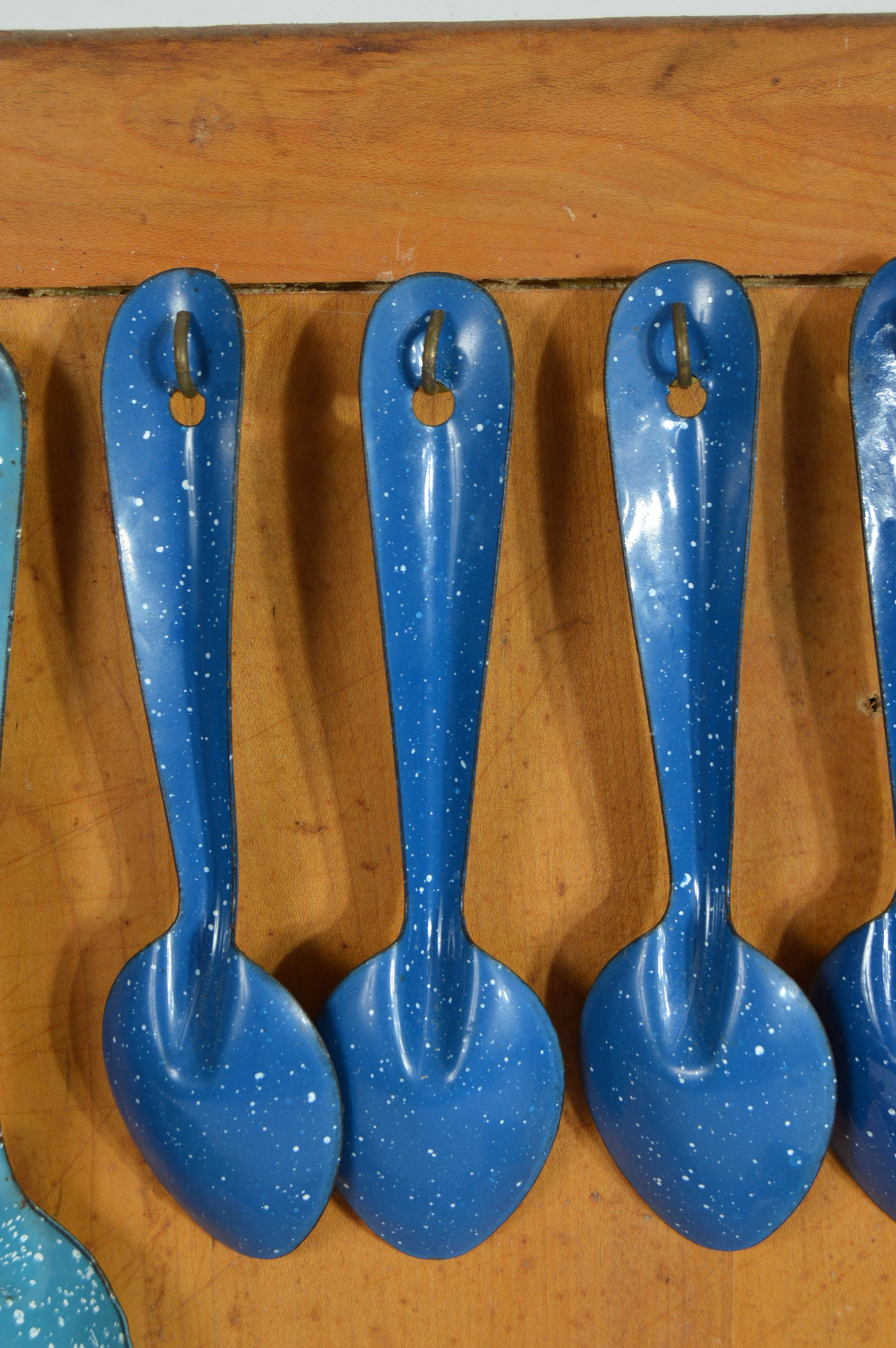 Collection of Speckled Enamel Ware Utensils Mounted on a Cutting Board
