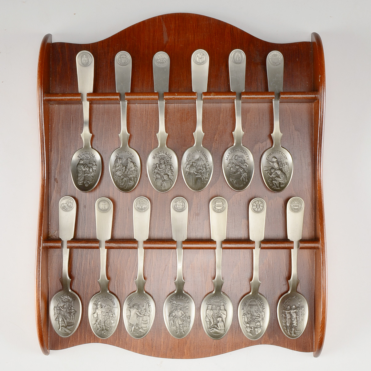 Collection of Thirteen Original State Spoons Displayed in Wooden Shelf