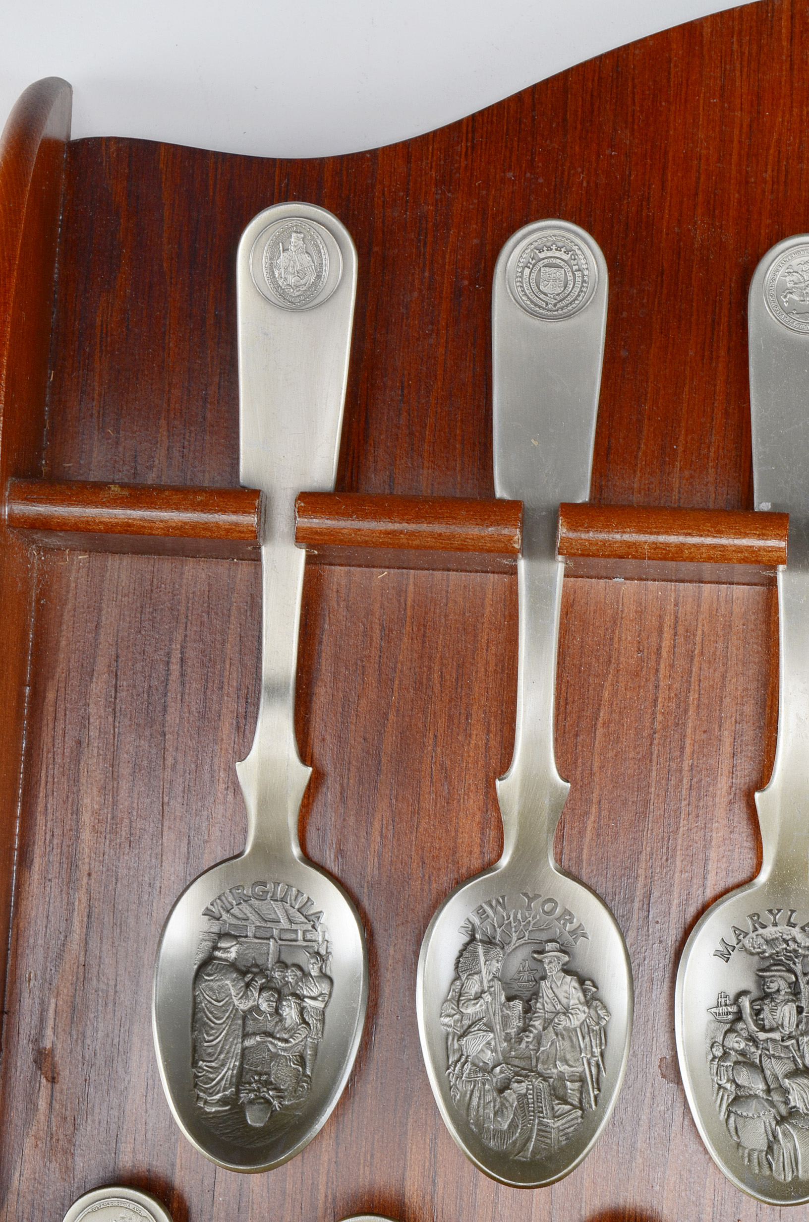 Collection of Thirteen Original State Spoons Displayed in Wooden Shelf