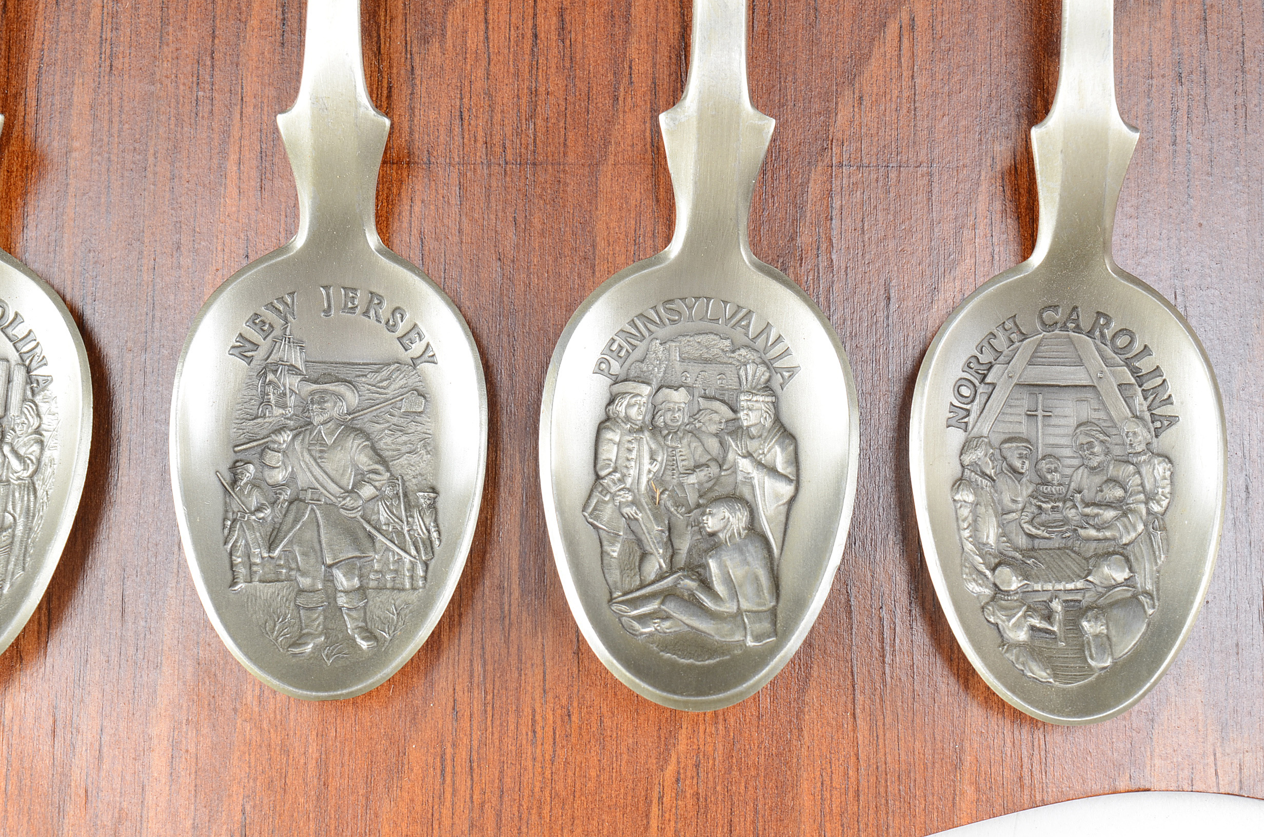 Collection of Thirteen Original State Spoons Displayed in Wooden Shelf