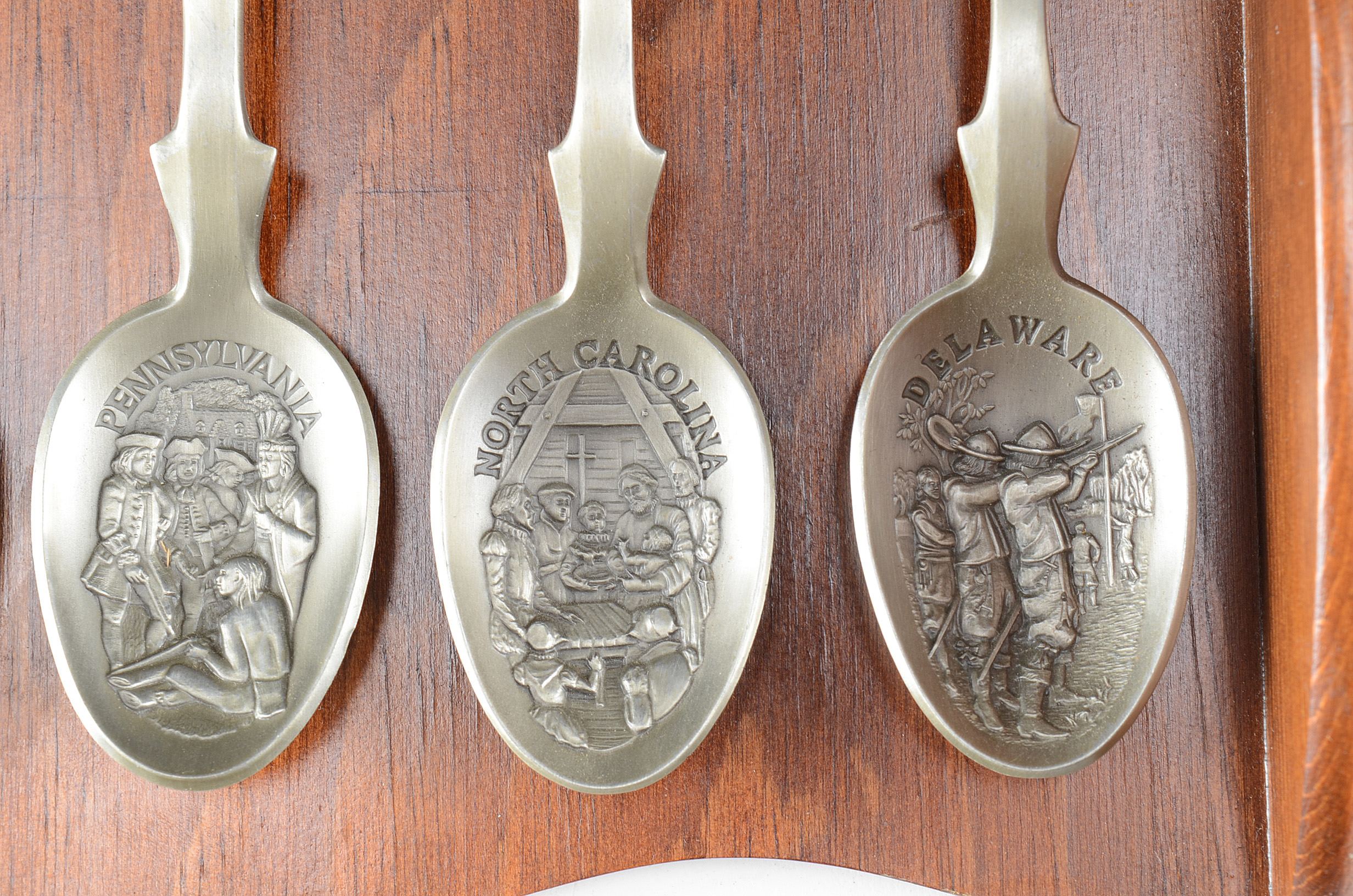 Collection of Thirteen Original State Spoons Displayed in Wooden Shelf