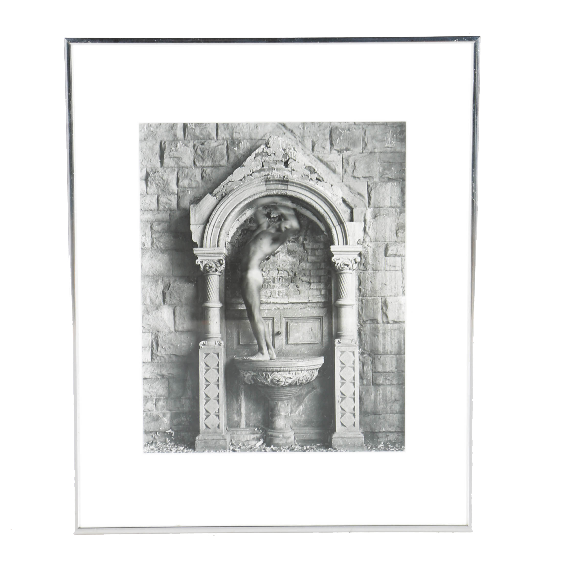 Black and White Photograph of a Nude Figure Under an Arch