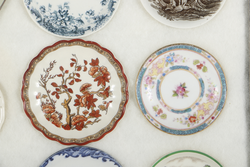 Twelve Porcelain Butter Pats In Glass Top Display Case