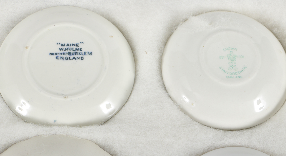 Twelve Porcelain Butter Pats In Glass Top Display Case