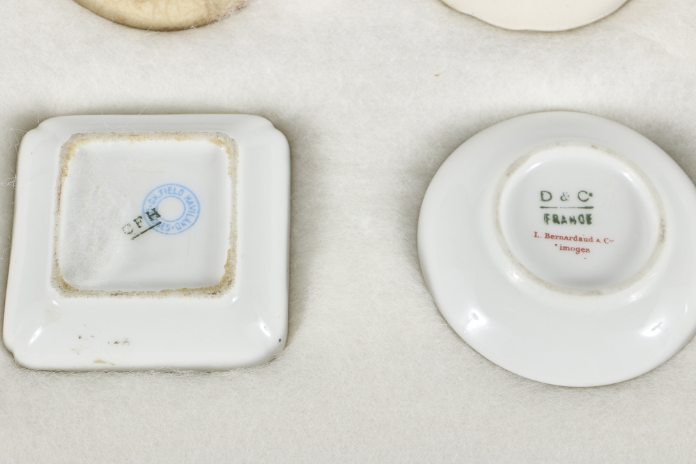 Twelve Porcelain Butter Pats In Glass Top Display Case