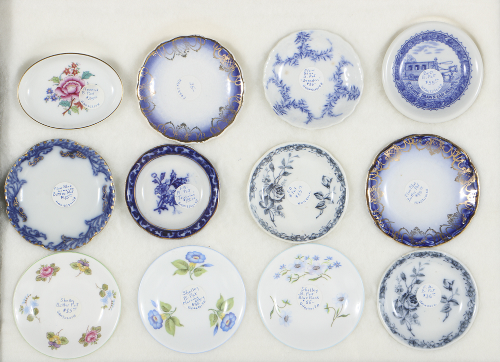 Twelve Porcelain Butter Pats In Glass Top Display Case