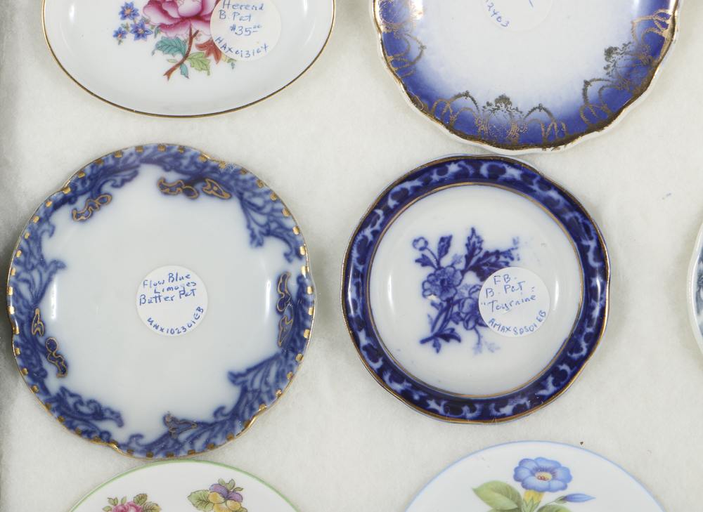 Twelve Porcelain Butter Pats In Glass Top Display Case