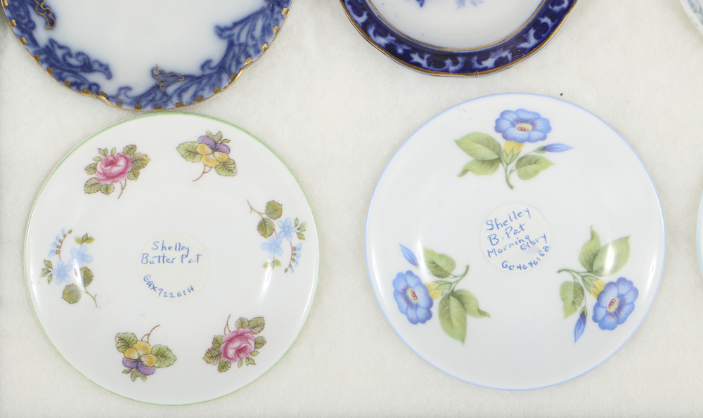 Twelve Porcelain Butter Pats In Glass Top Display Case