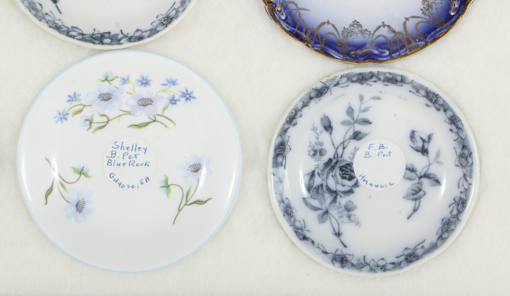 Twelve Porcelain Butter Pats In Glass Top Display Case