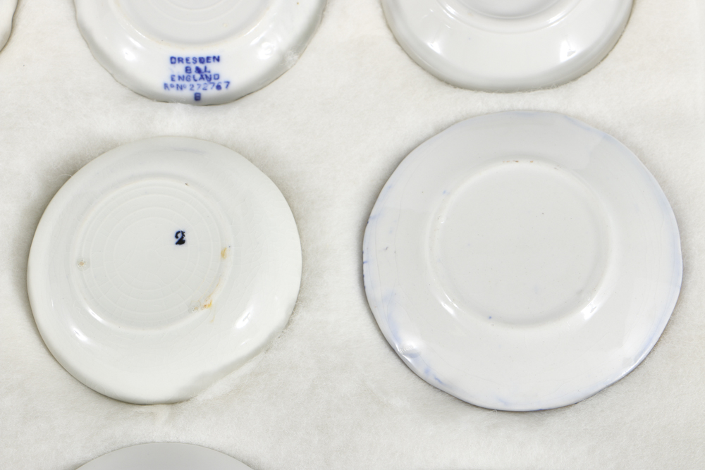 Twelve Porcelain Butter Pats In Glass Top Display Case