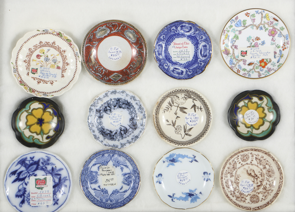 Twelve Porcelain Butter Pats In Glass Top Display Case