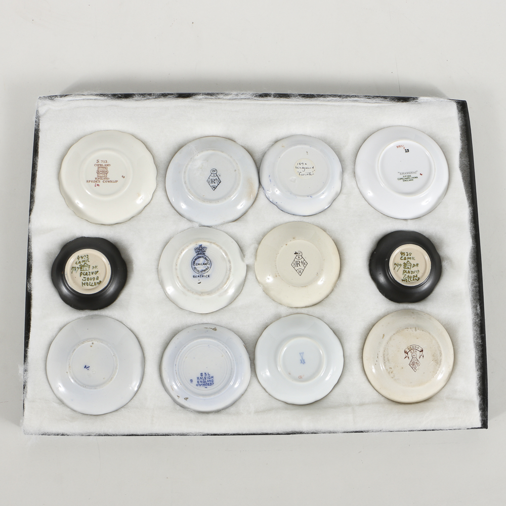 Twelve Porcelain Butter Pats In Glass Top Display Case