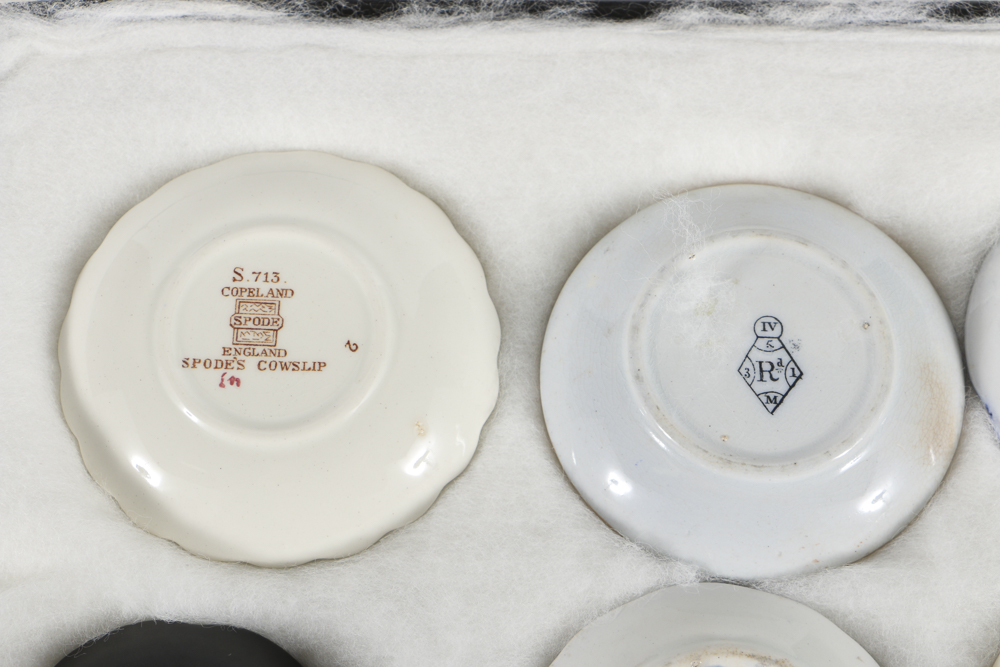 Twelve Porcelain Butter Pats In Glass Top Display Case