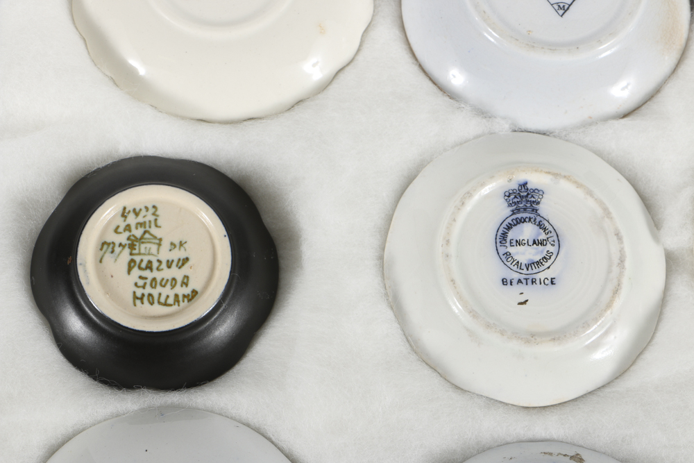 Twelve Porcelain Butter Pats In Glass Top Display Case